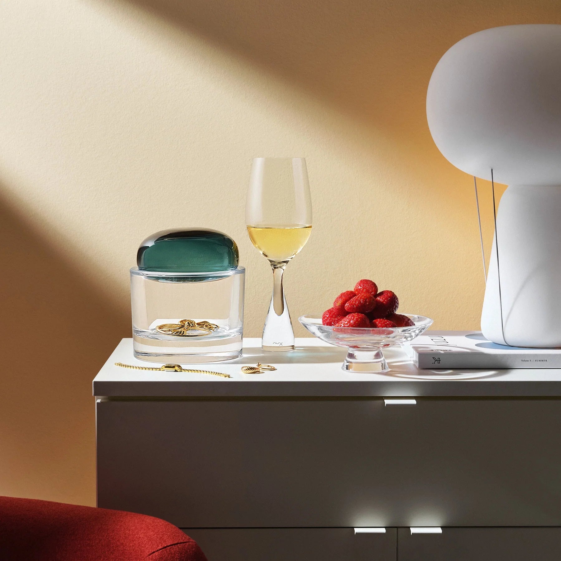 mælkehvid blow bordlampe på et sengebord med et champagneglas