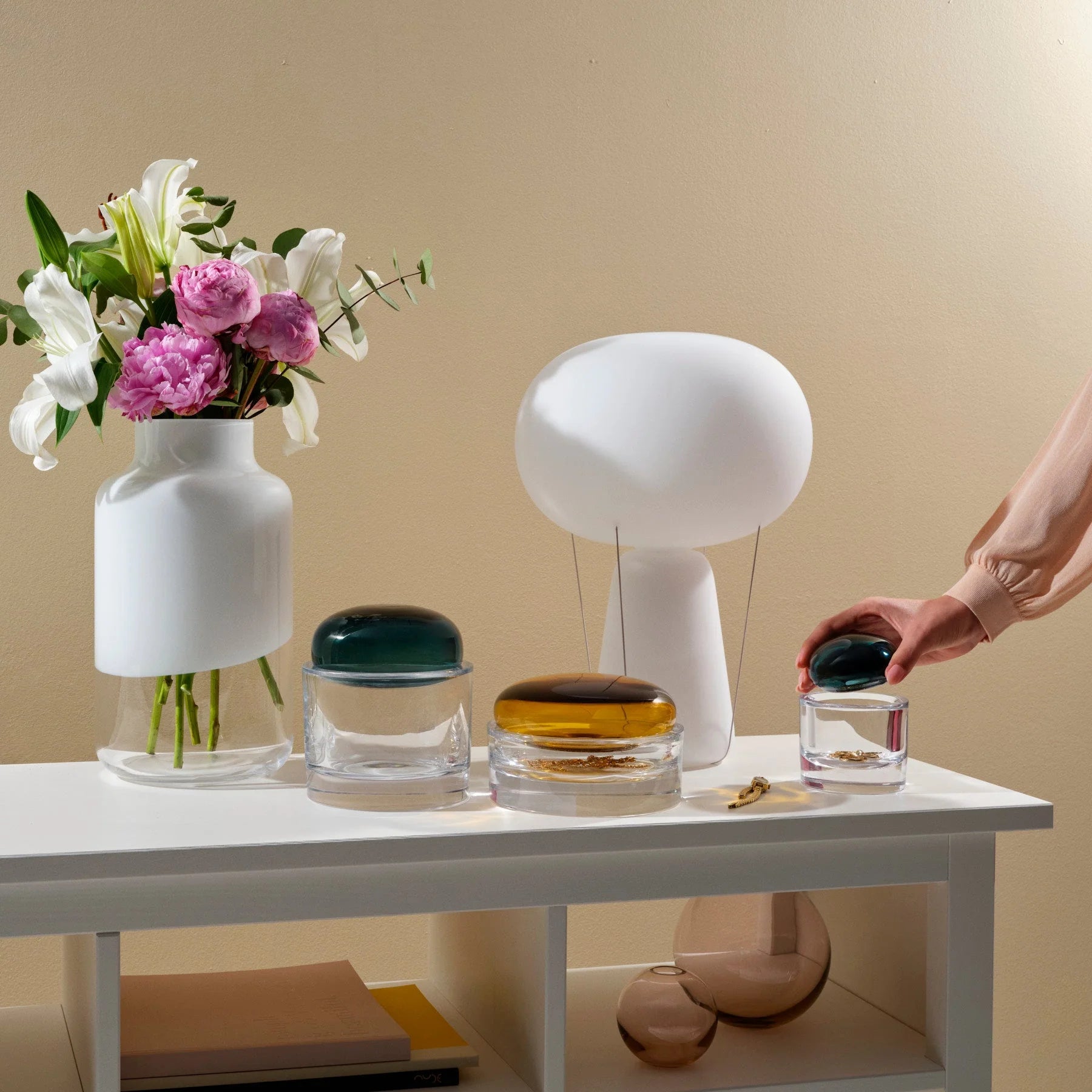 opal hvid bordlampe der hedder blow på en hvid reol med andre glas 